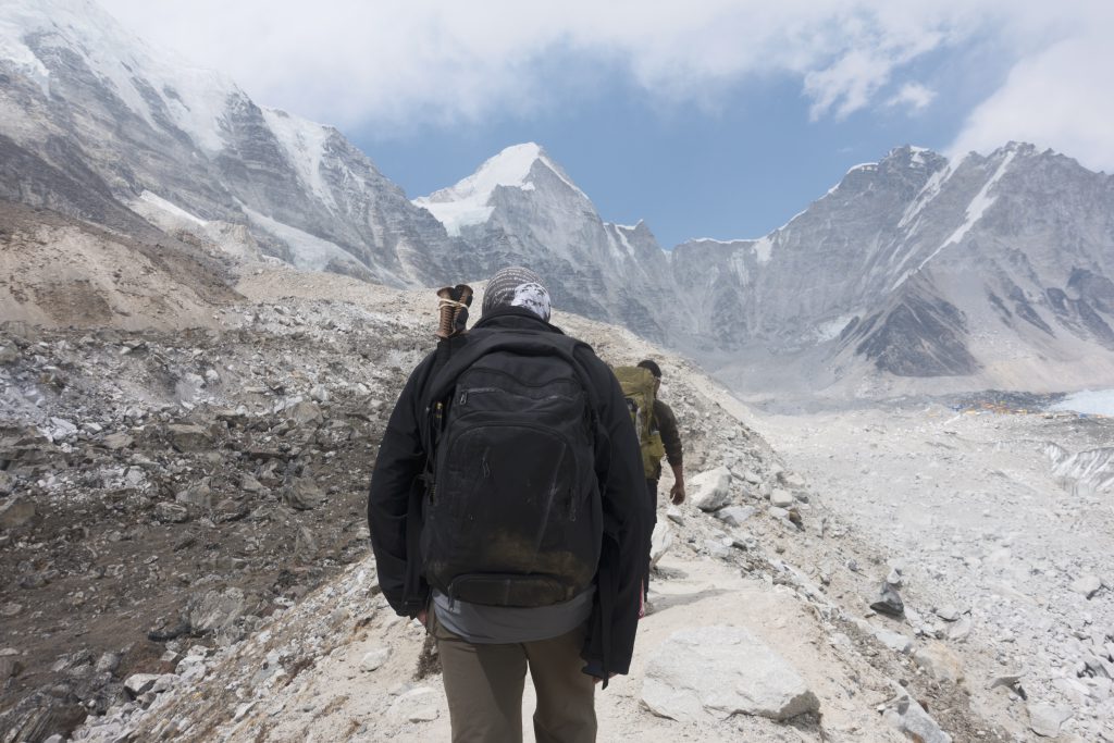 Two people walking along a mountain path.